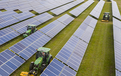 tractors between rows of solar panels