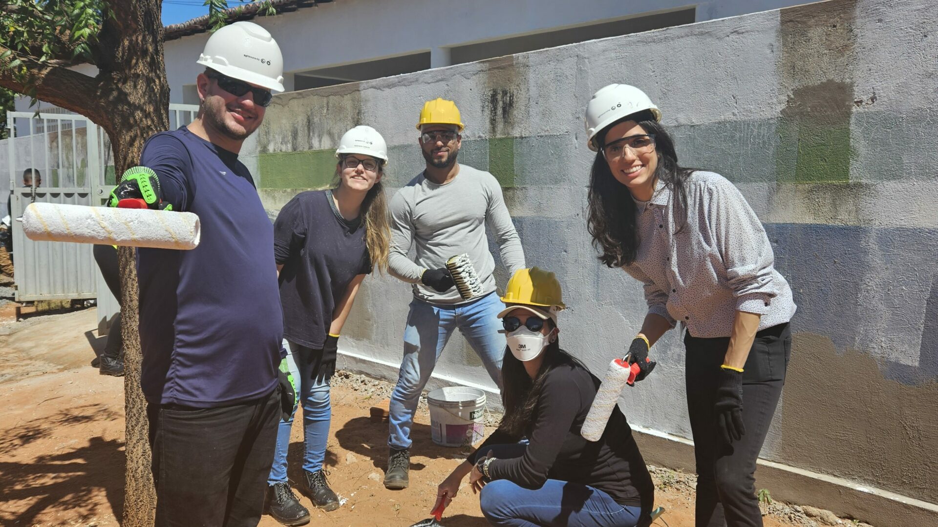 Brazil team volunteers smiling whilst painting wall