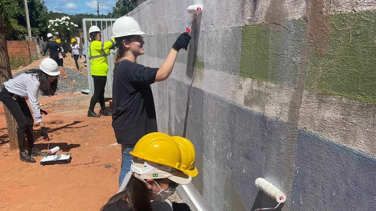 Brazil team volunteers smiling and painting a wall