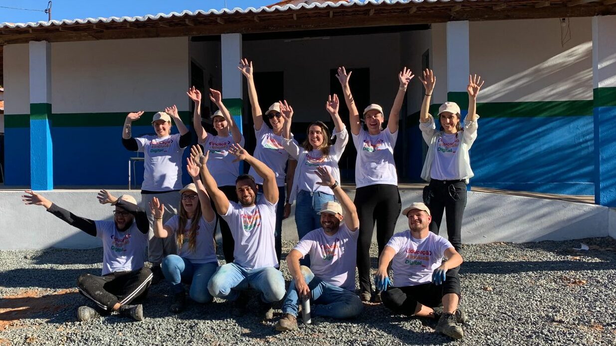 Brazil team volunteers smiling and celebrating with their hands in the air in front of the school