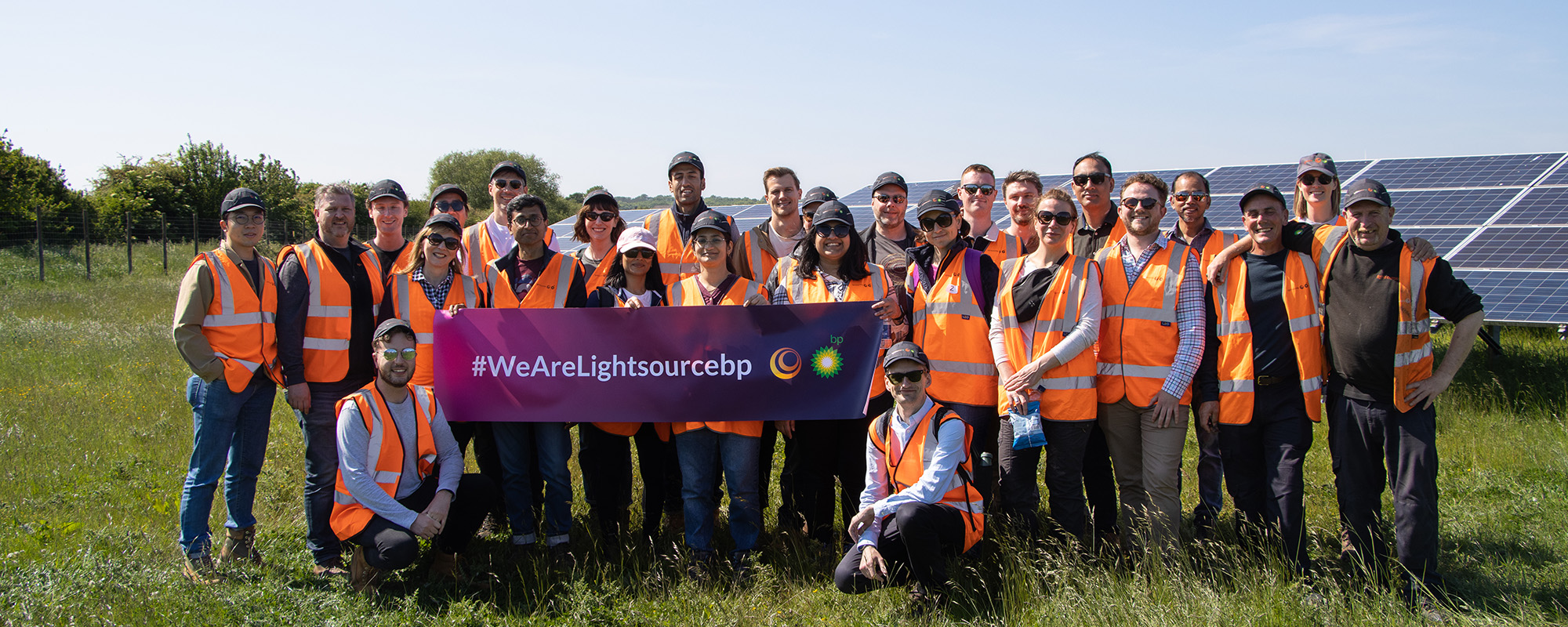 Lightsource bp team members group photo at a solar project holding a Lightsource bp banner