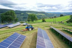 Tractor ploughing through fields of solar panels