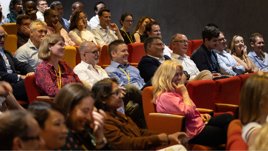 Group of people sitting on red chairs in a theatre or hall