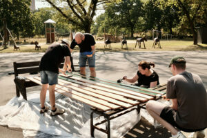 Four Lightsource bp volunteers painting wooden boards for the football goal-wall