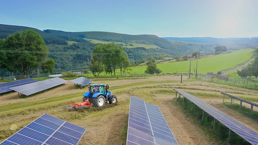 A tractor haybaling on a solar farm