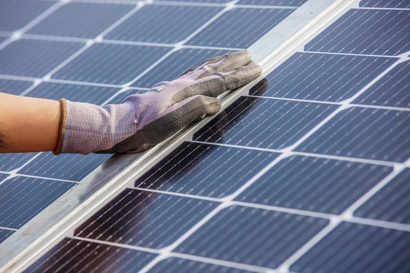 A close up of a gloved hand on a solar panel